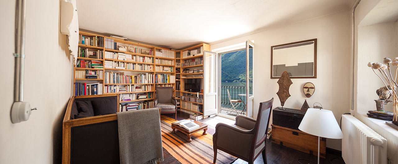 Obývací pokoj s obrovskou knihovnou, čajovým stolkem a nábytkem namířeným mimo stěnu, na které je TV