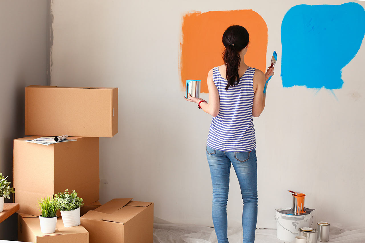 Mladá žena maluje interiér na kombinaci oranžové a modré