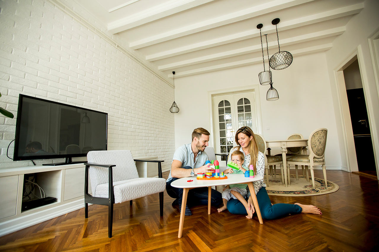 Šťastná rodina v moderním obývacím pokoji s tradičním jídelním setem