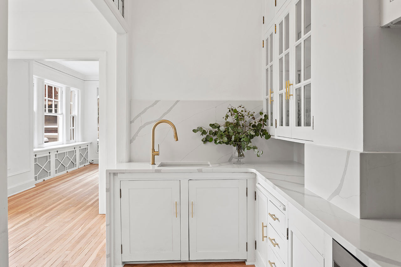 Moderní bílá rohová kuchyně s dřezem a skříňkami