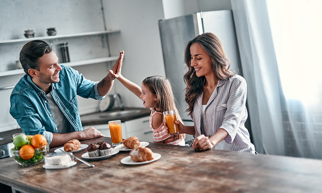 Šťastná mladá rodina u snídaně v moderní kuchyni
