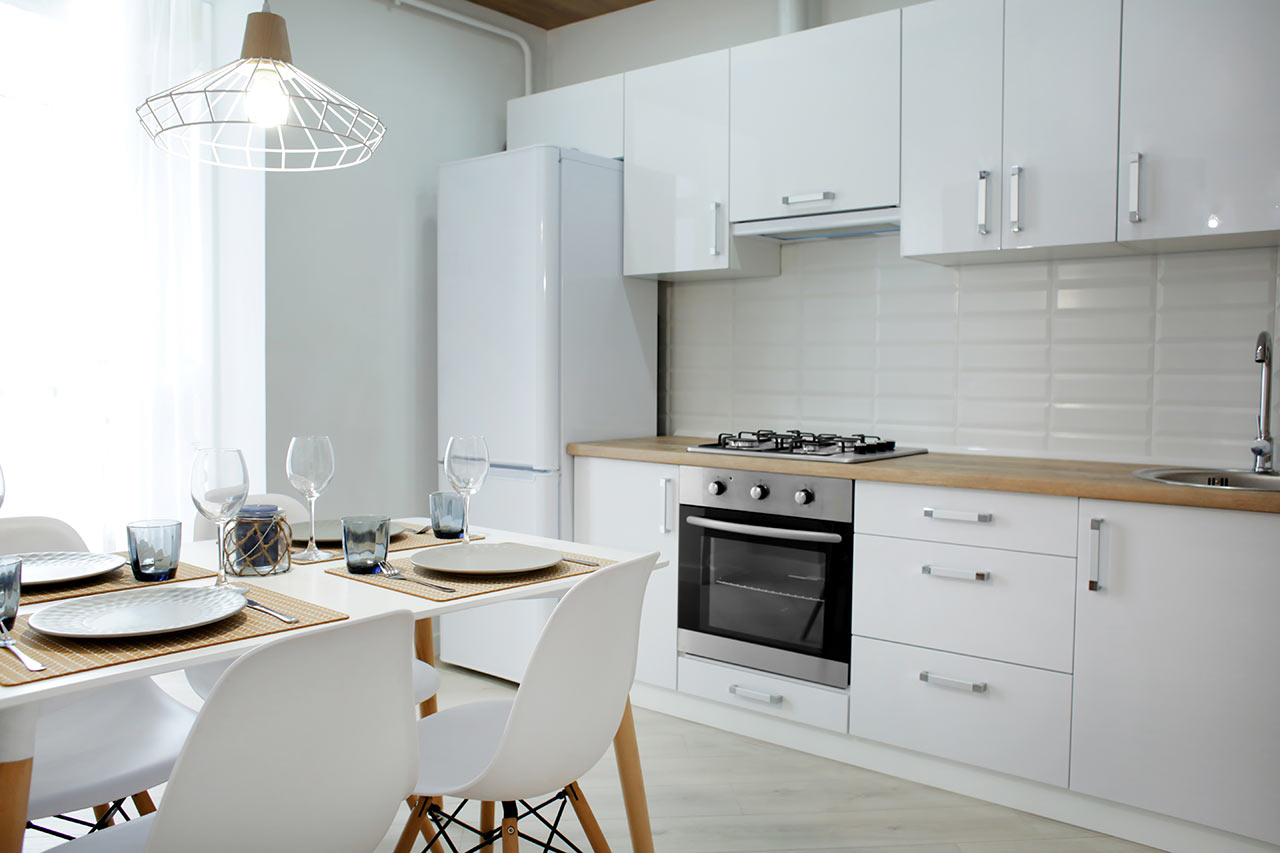 Moderní kuchyně s bílými skříňkami a dřevěnou pracovní deskou